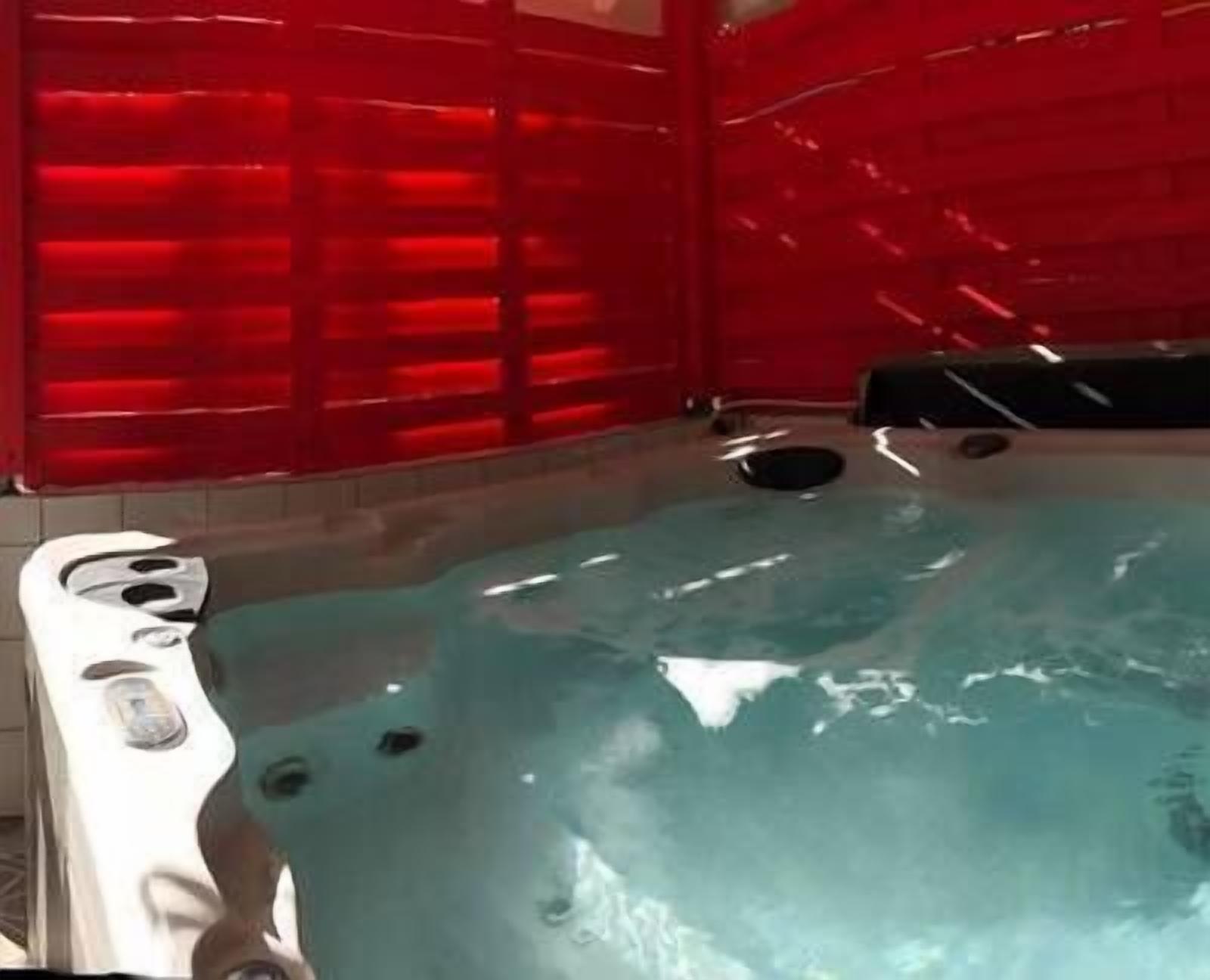 Un bain à remous doté d’une structure rouge et d’un sol carrelé.