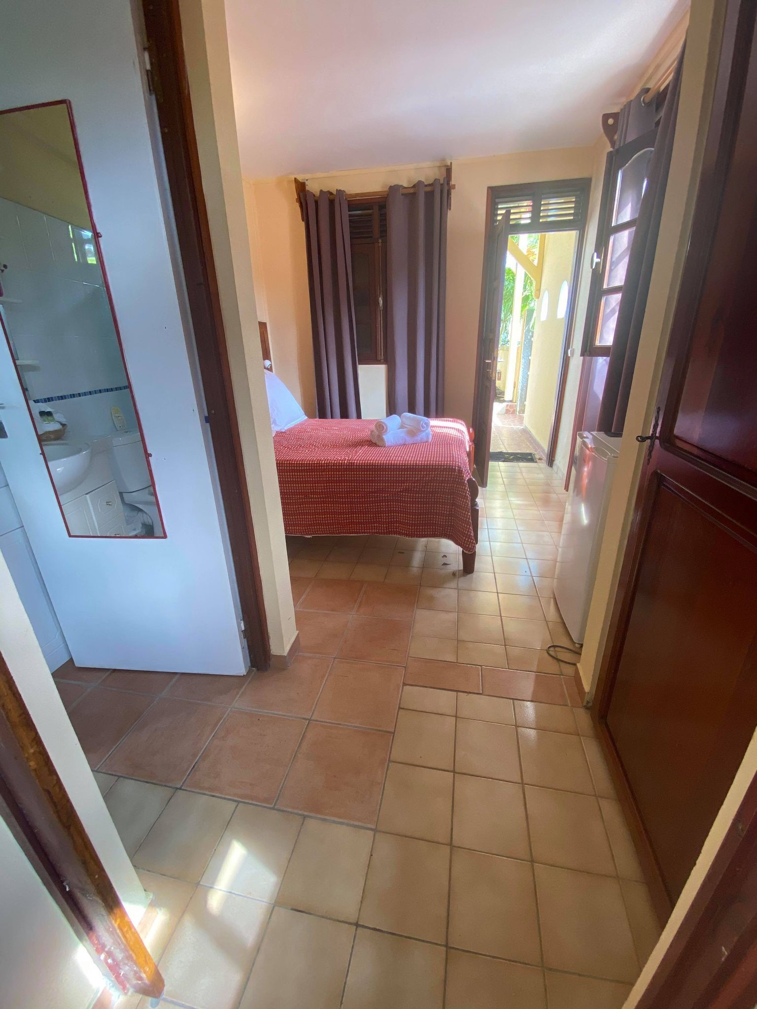 Un pasillo estrecho que da a un dormitorio con cama, un baño pequeño y vistas al exterior.