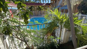 Ein Pool, umgeben von üppiger Vegetation und einem Gebäude mit rotem Dach.