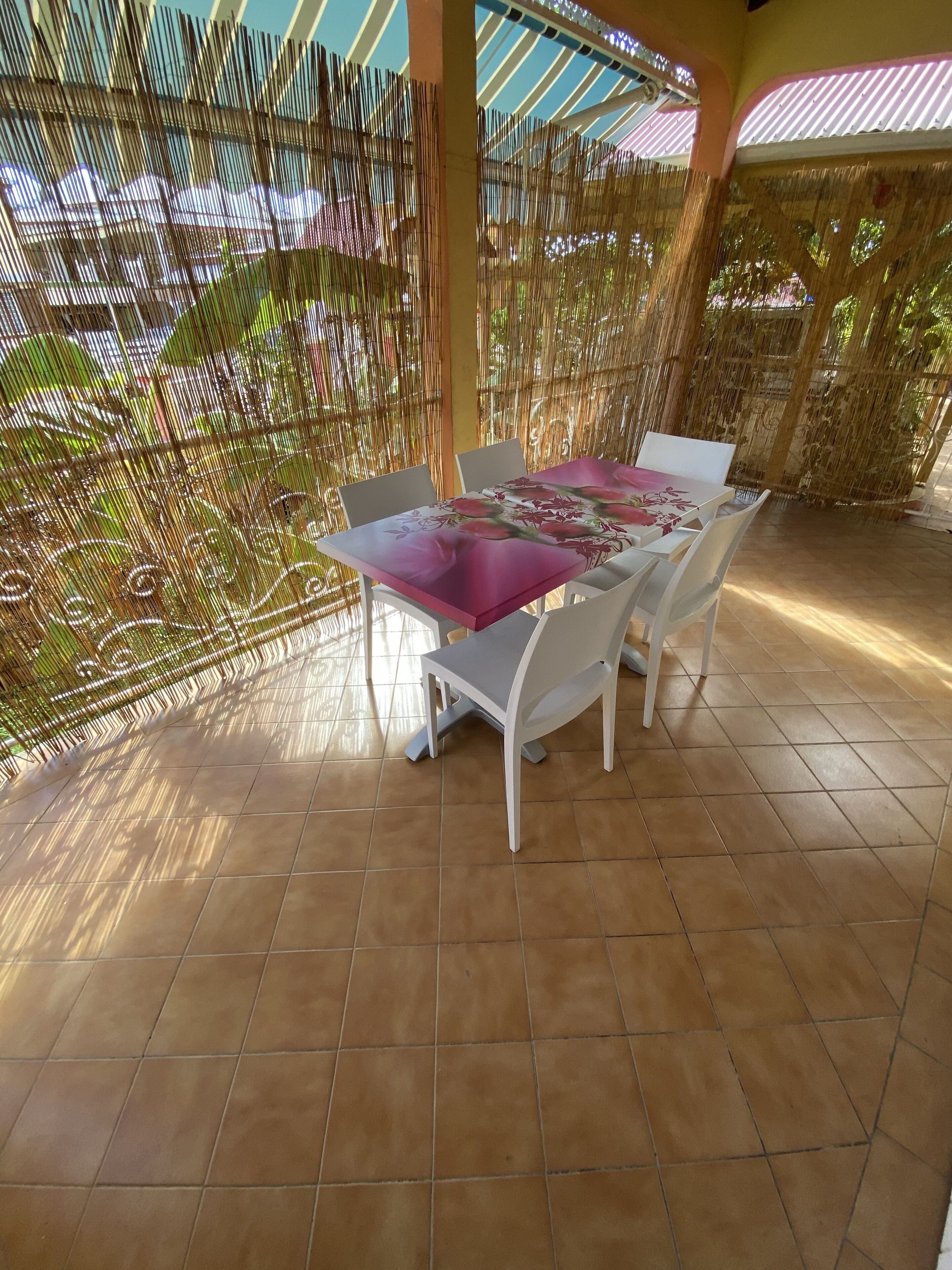 Eine Terrasse im Freien mit Tisch und Stühlen, umgeben von einem Bambuszaun.