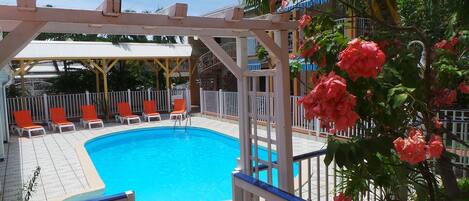 Una piscina al aire libre, sombrillas, tumbonas