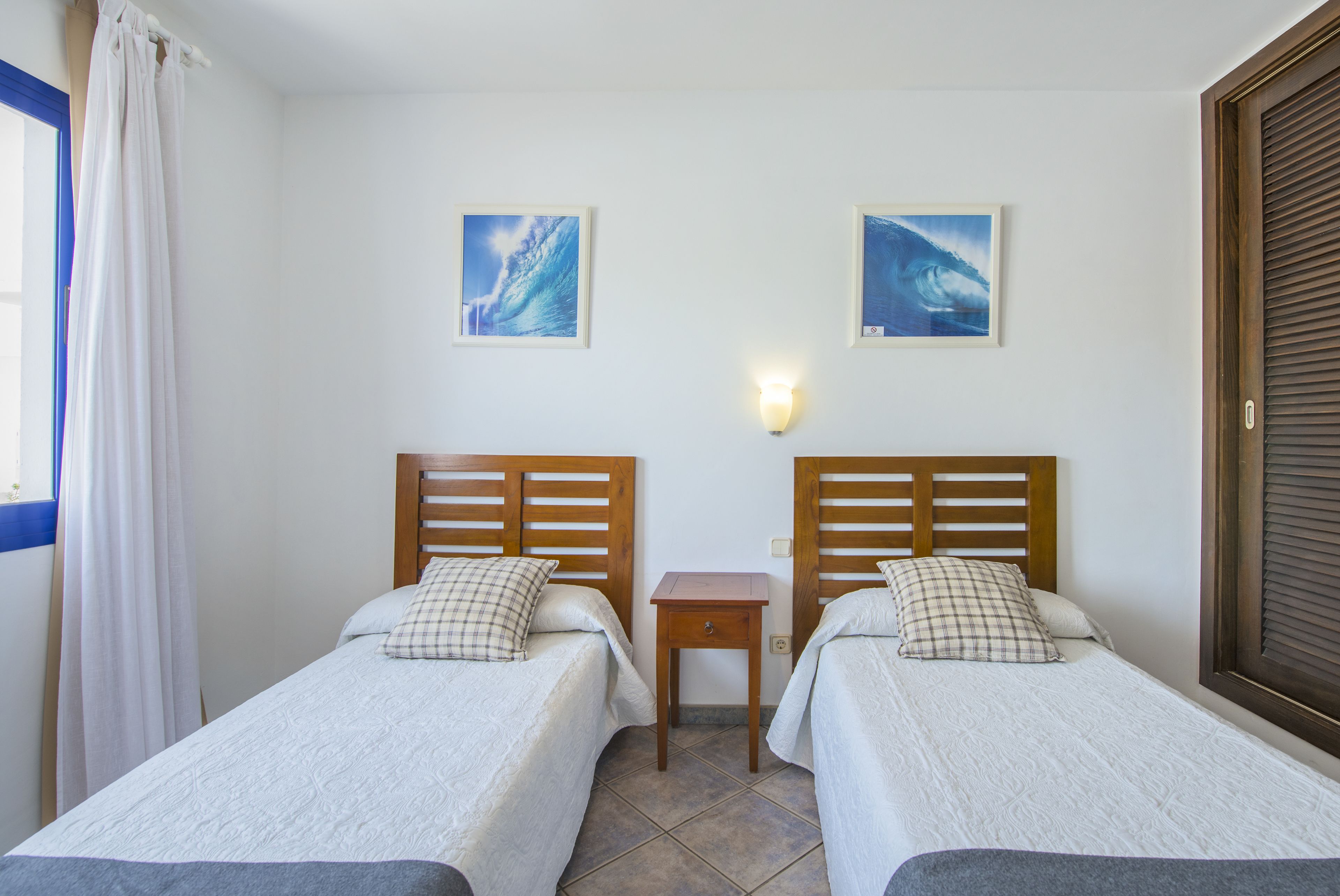 Una stanza con due letti, un comodino e due quadri appesi al muro.