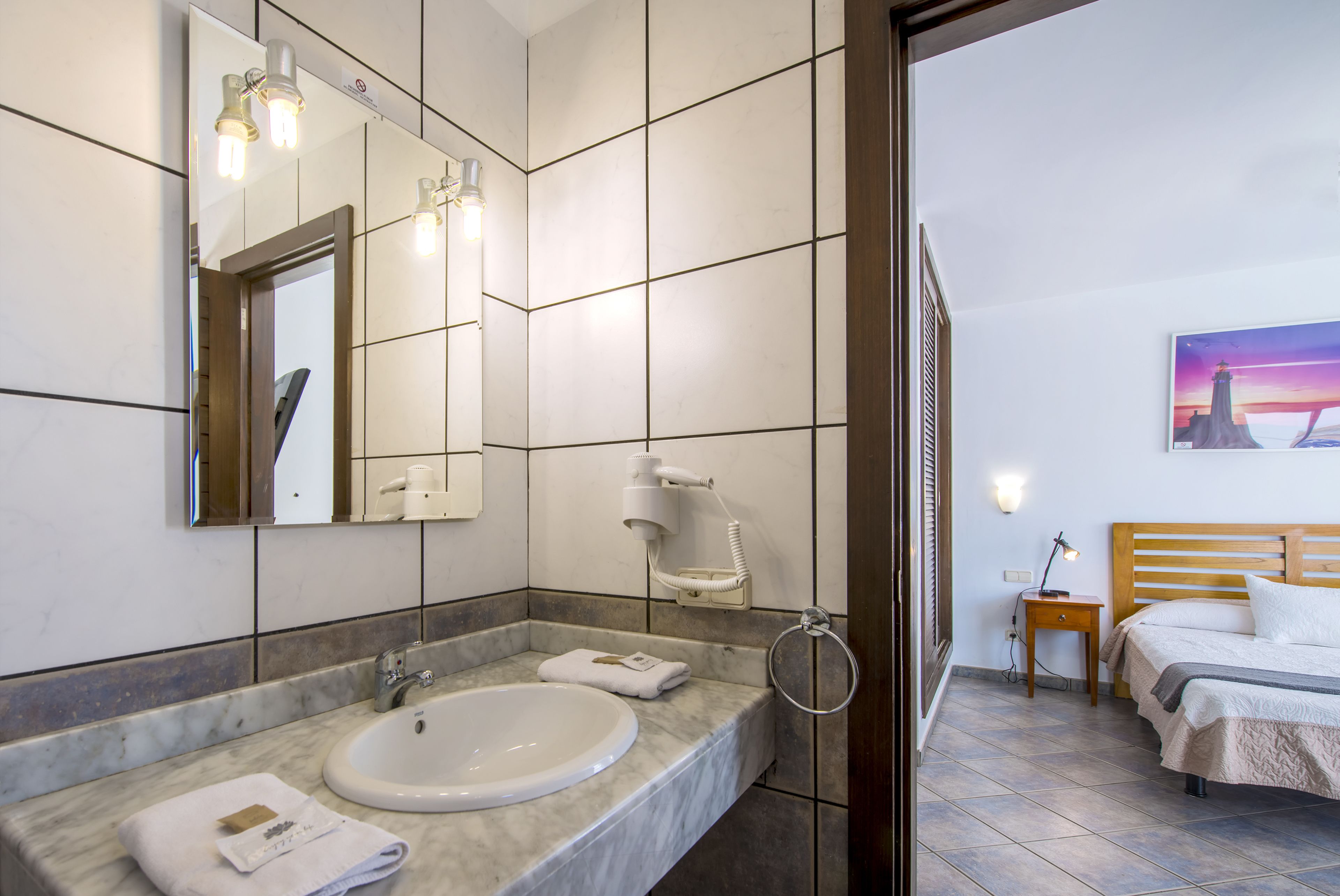 Ein Badezimmer mit Marmorwaschbecken, einem Spiegel und einem an der Wand montierten Fön.