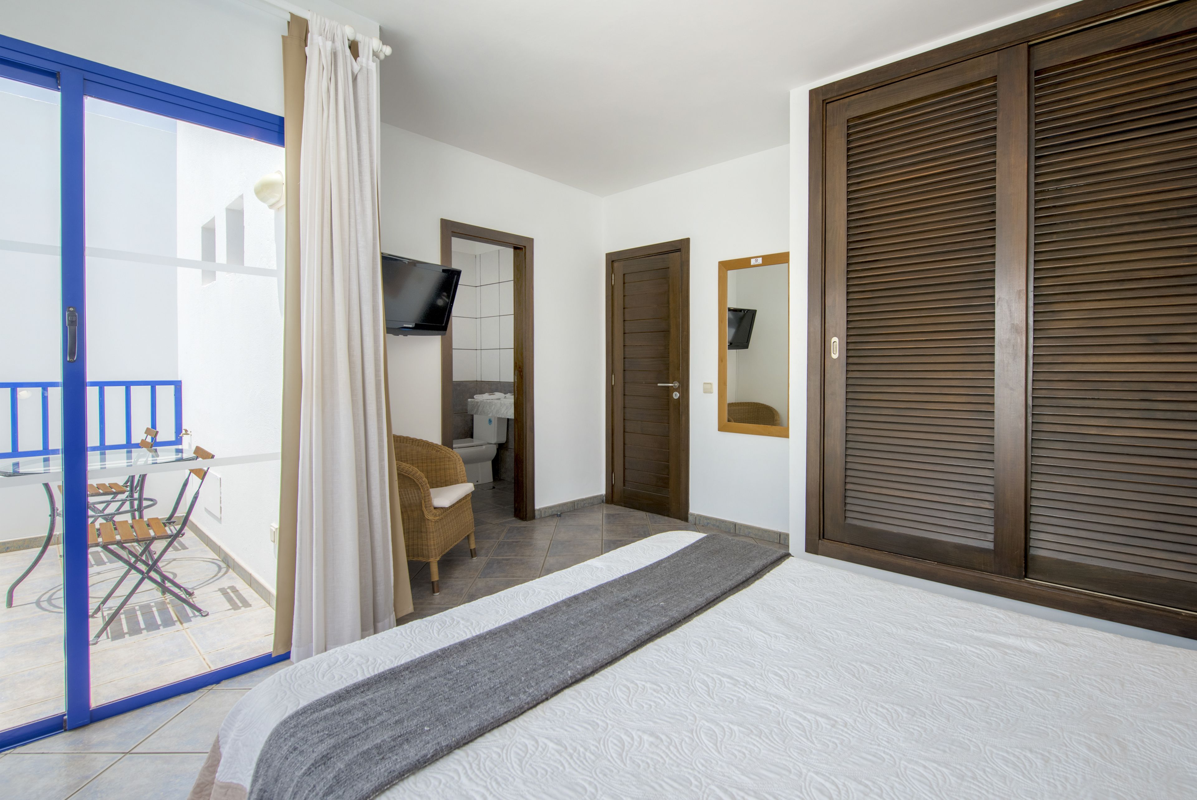 A bedroom with a bed, a wardrobe, a bathroom, and a balcony.