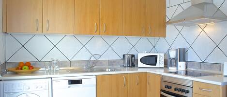 A compact kitchen with wooden cabinets, a dishwasher, an oven, and a microwave.