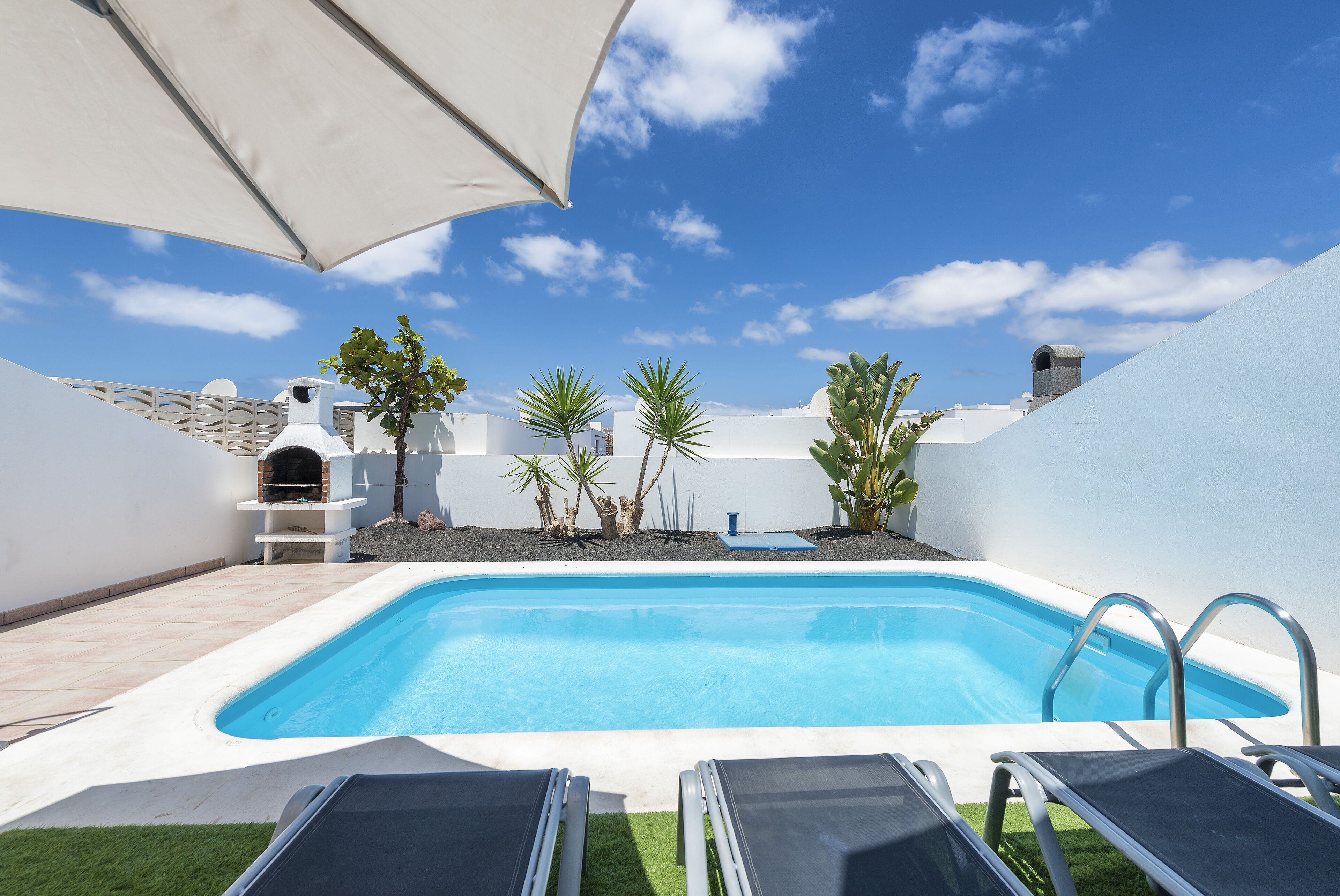 Una piscina con sillones de descanso y zona de barbacoa.