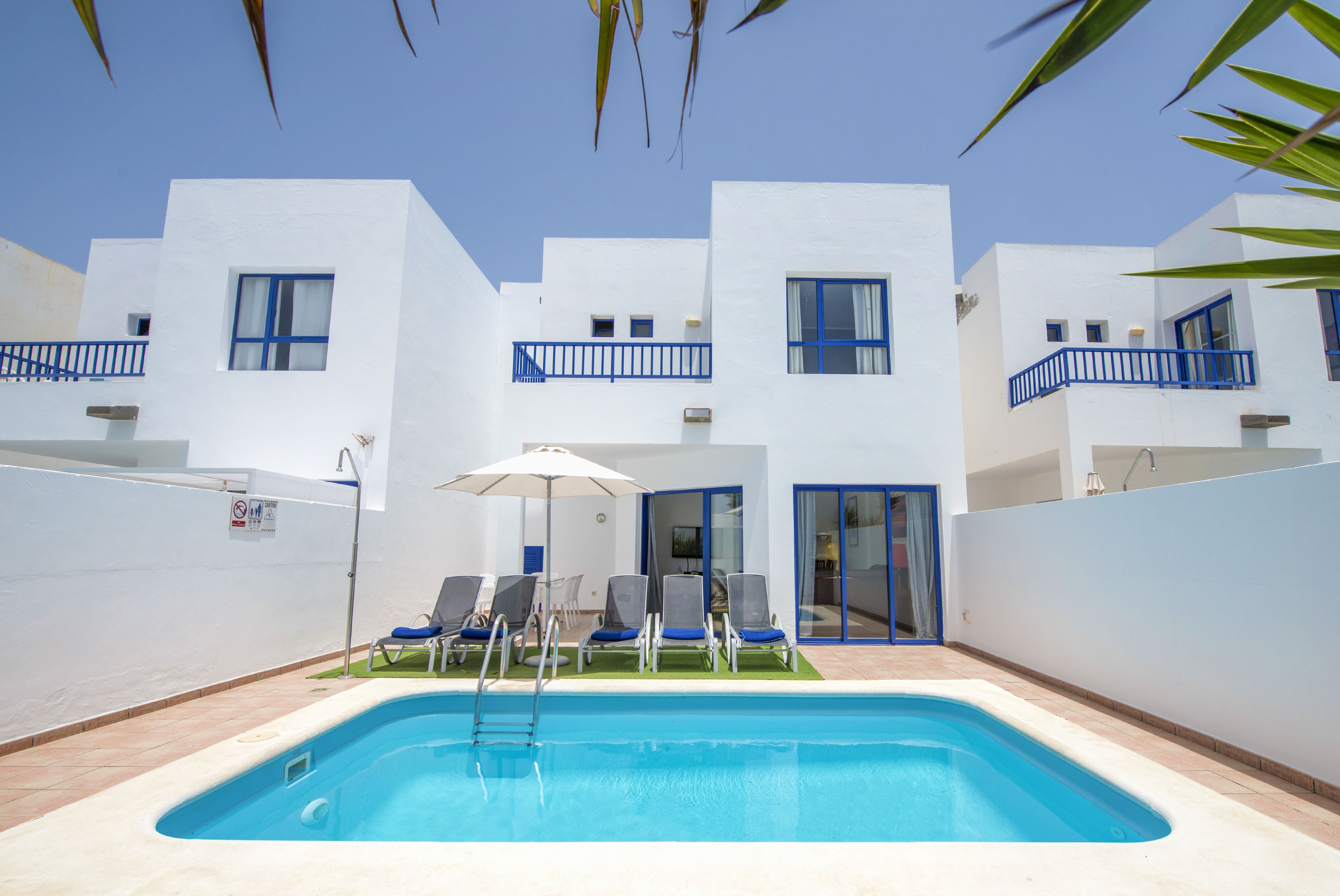 A modern building with a swimming pool, blue railings, and outdoor seating.
