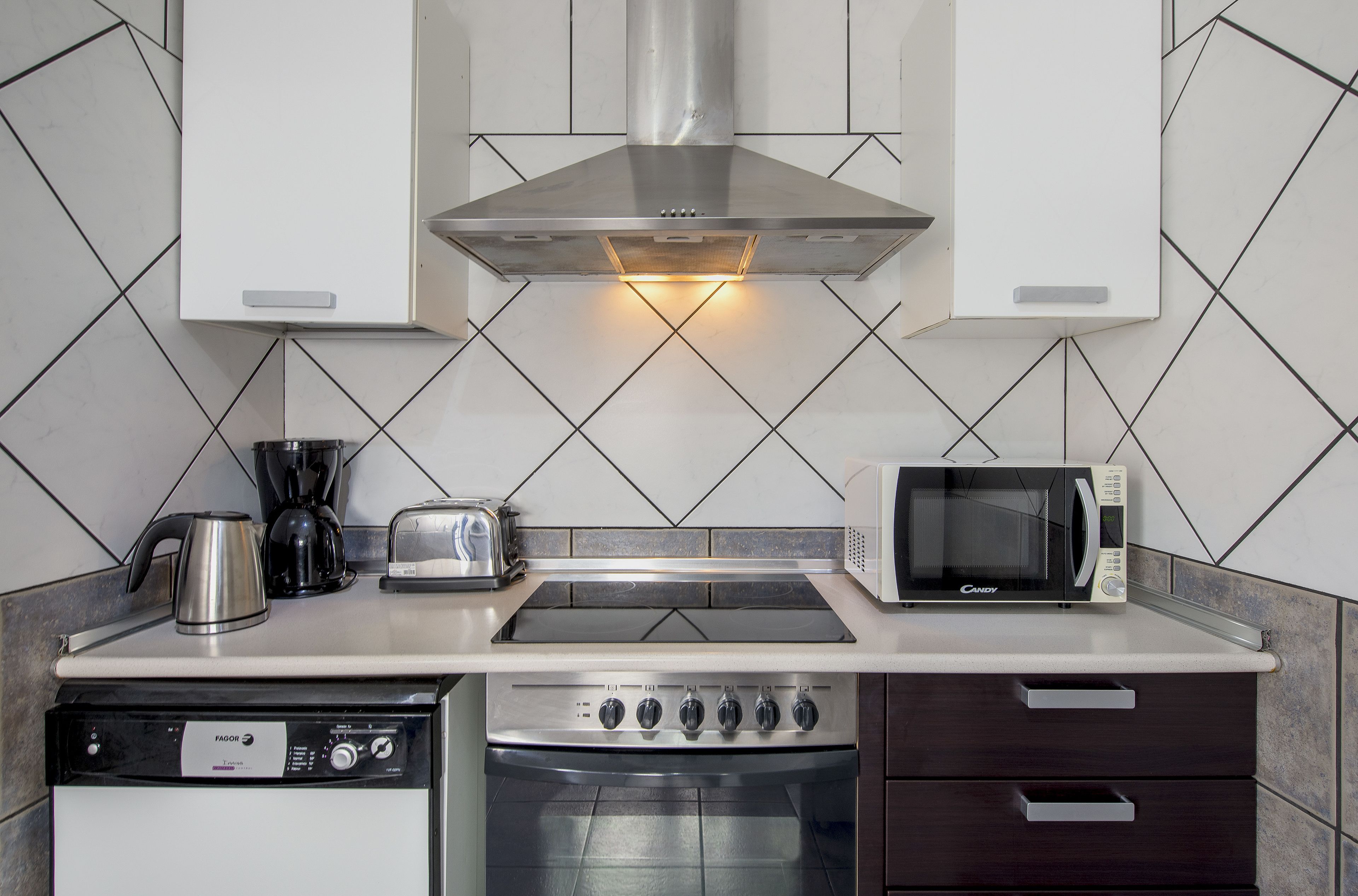 A kitchen with a dishwasher, stove, microwave, and toaster.