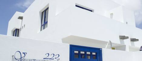 A white building with a blue door and windows, labeled "Villas del Puerto Rubicon 223".