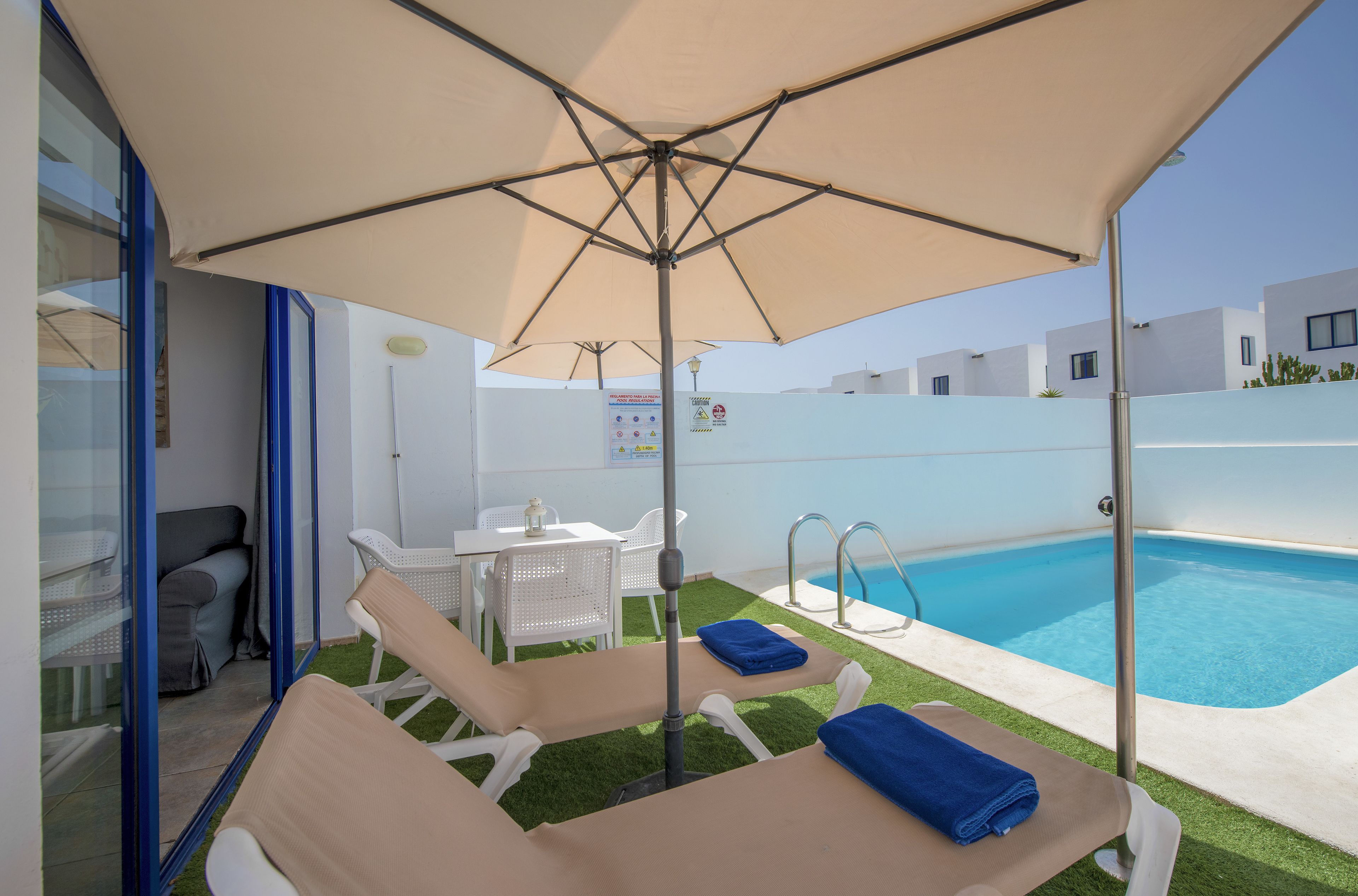 A poolside area with lounge chairs, a table, and umbrellas.