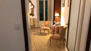 Ein Flur mit Fliesenboden, einer Tür, einem Spiegel, einem Tisch mit Lampe und zwei Stühlen.