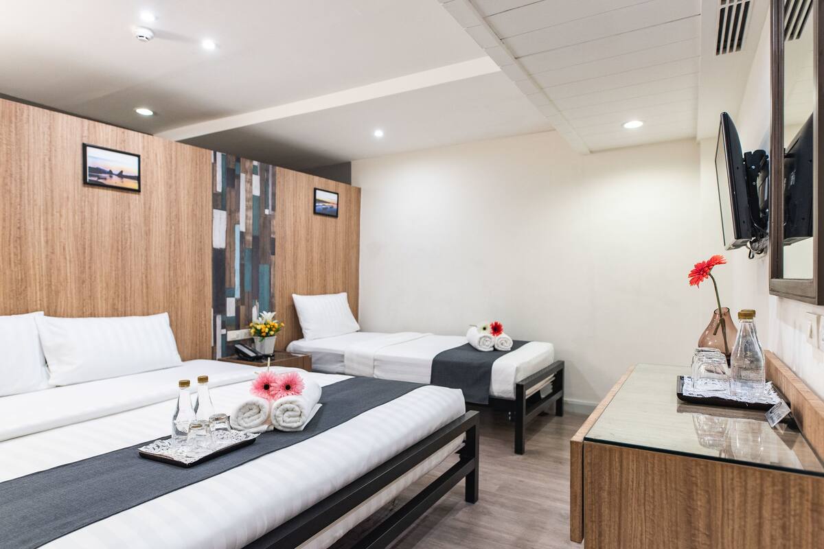 A hotel room with two beds, a small desk, and a mirror.