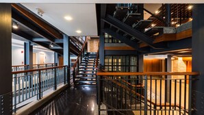 A multi-level interior with a central staircase, metal railings, and a polished floor. - D&D Inn Khaosan (Bangkok)