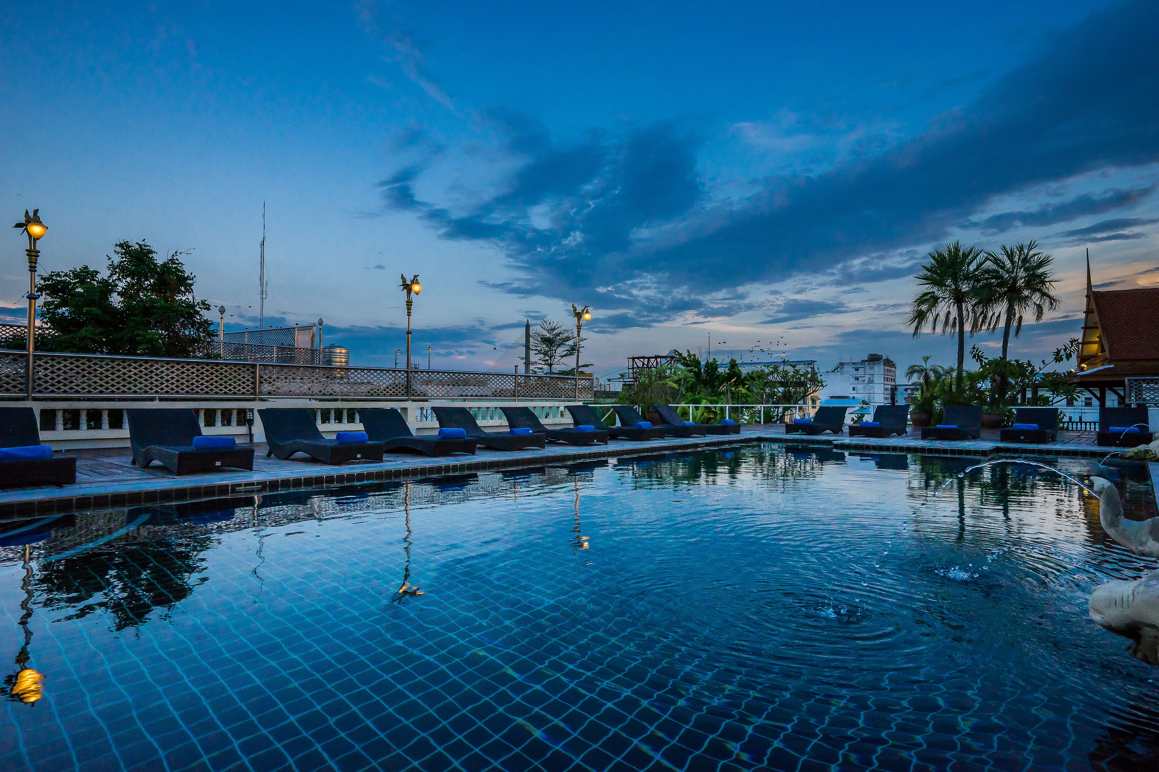 A swimming pool with lounge chairs and a view of the sky.