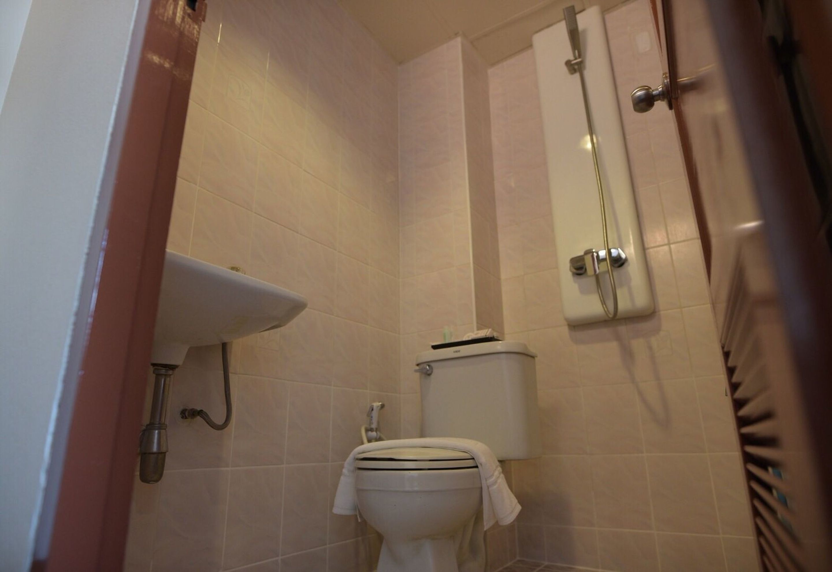 Een compacte badkamer met toilet, wastafel en douche.