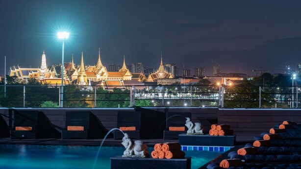 A rooftop pool area with a view of a grand, illuminated temple complex in the background. - D&D Inn Khaosan (Bangkok)