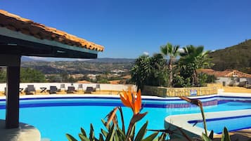 Una piscina al aire libre, sillones reclinables de piscina