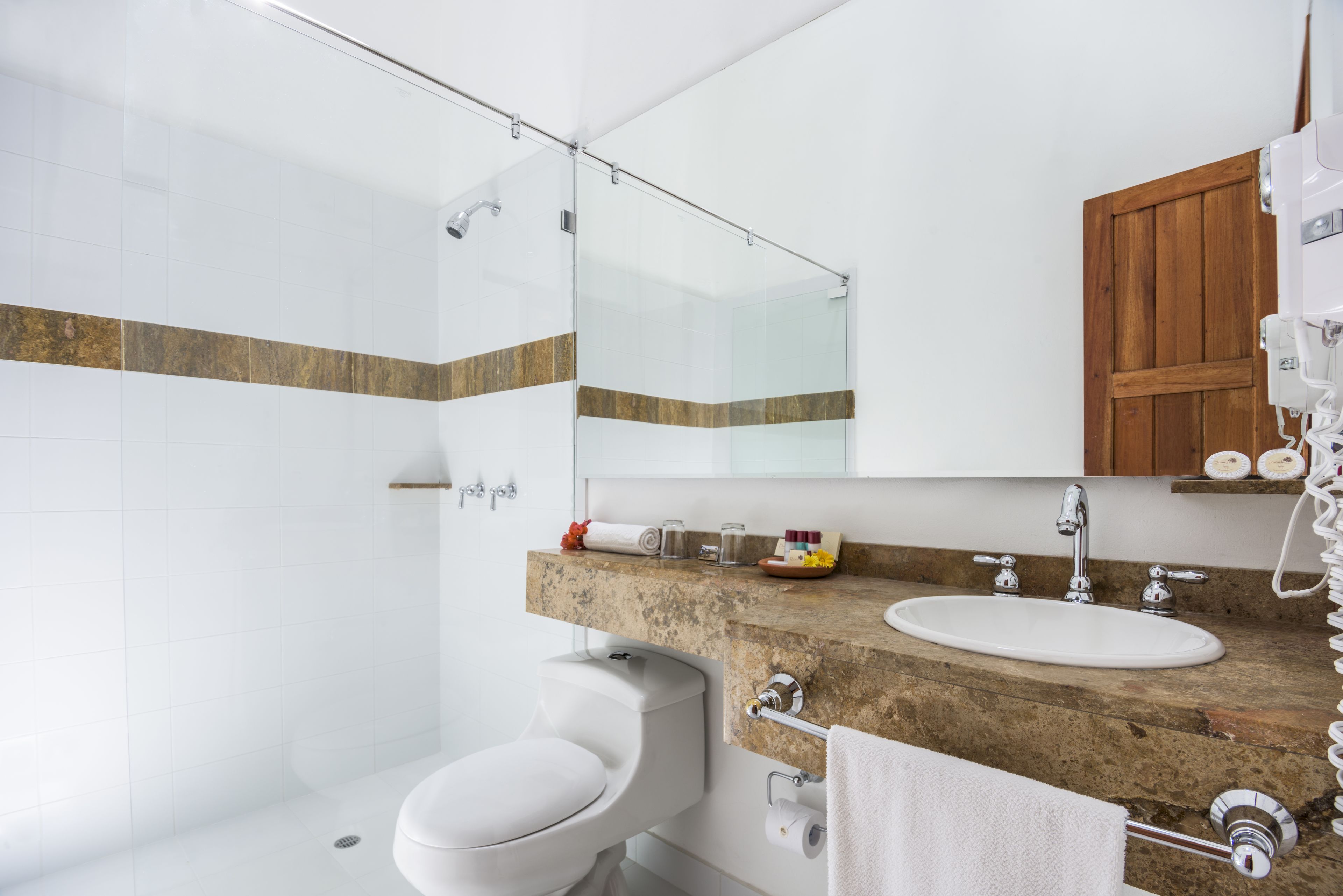 A modern bathroom with a shower, toilet, sink, and a wooden cabinet above the sink.