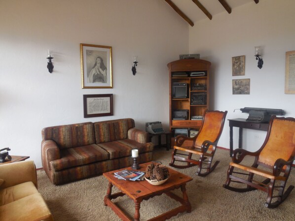 Una sala de estar acogedora con un sofá, sillones, una mesa de centro y una estantería.