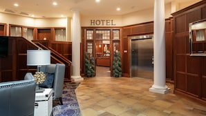 A hotel lobby with a reception desk, a staircase, and a large column. - Bicycle Street Inn (Mackinac Island)