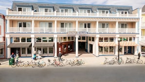 A multi-story hotel with a balcony on the second floor, a sign for 'Biker Street Inn & Suites', and bicycles parked outside. - Bicycle Street Inn (Mackinac Island)