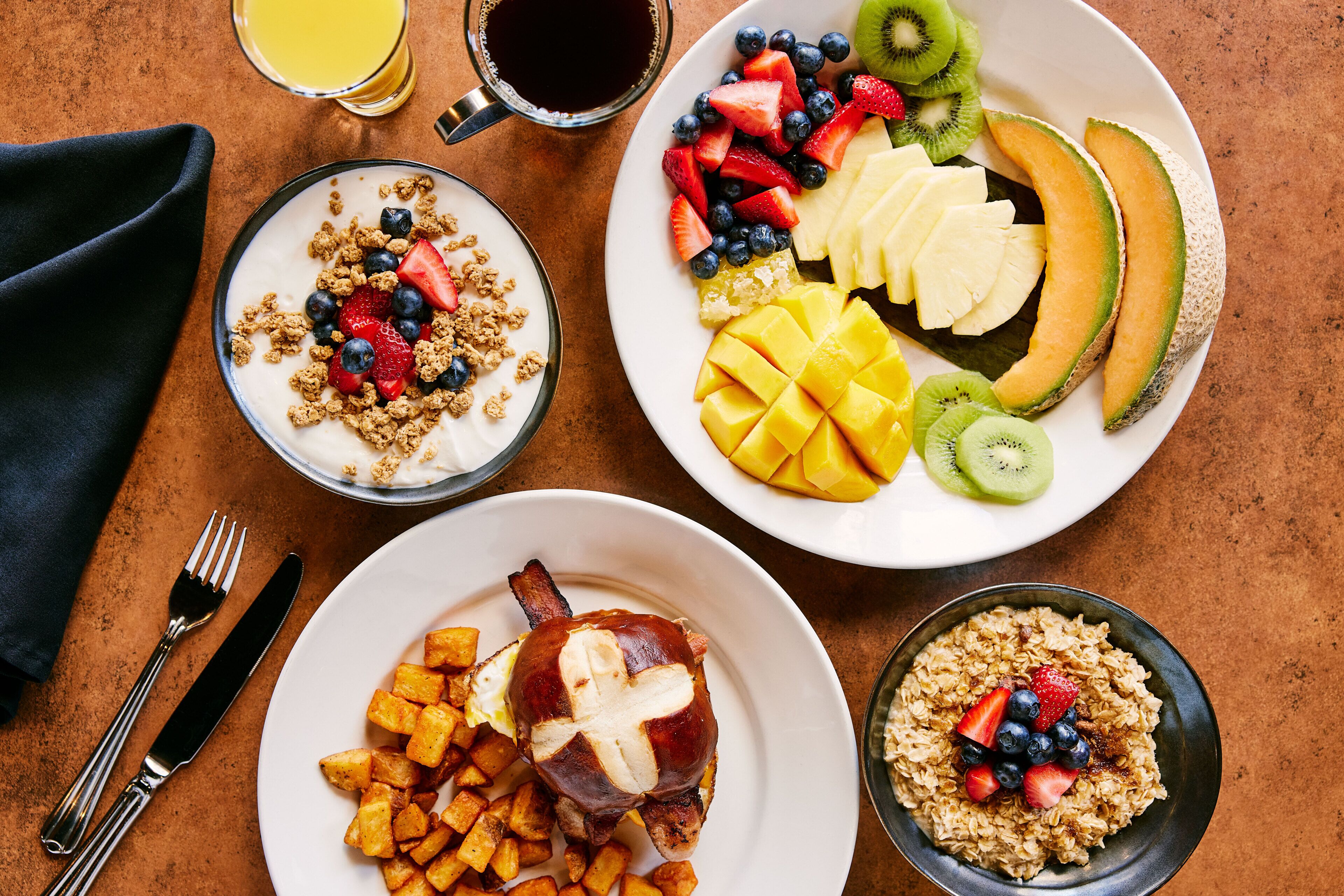 A breakfast setting with various dishes including fruit, yogurt, and a plate with a meat dish.