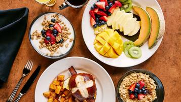 A breakfast setting with various dishes including fruit, yogurt, and a plate with a meat dish.