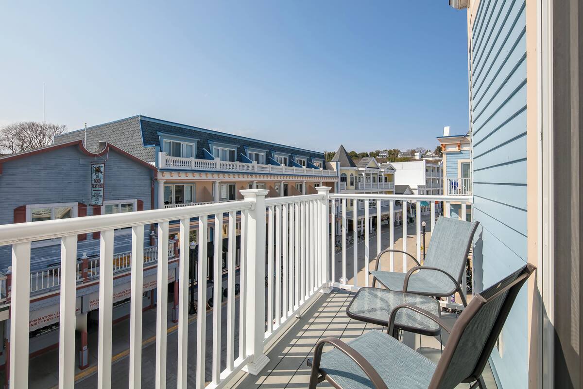 A balcony with two chairs and a table, overlooking a street with buildings.