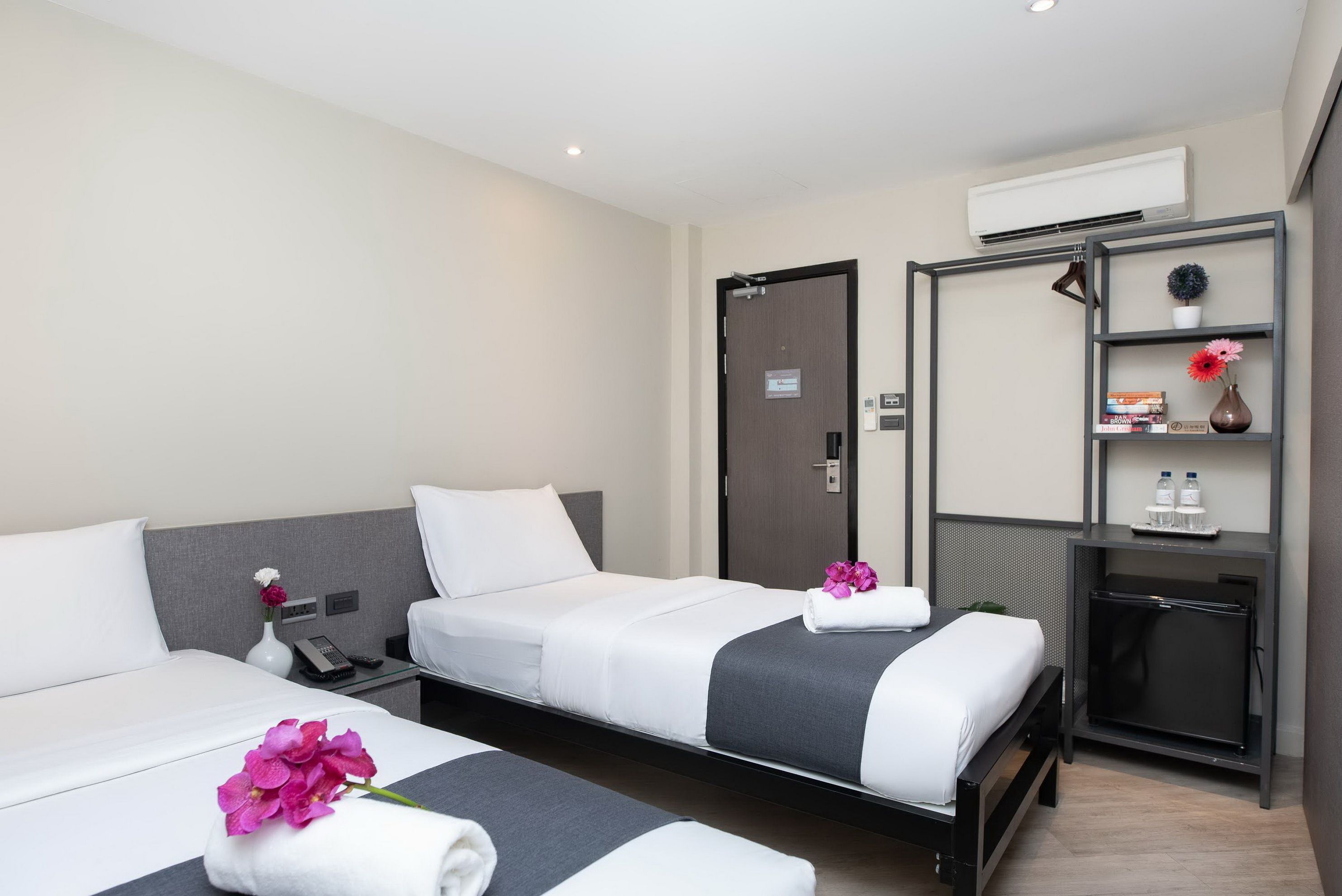 Une chambre d’hôtel avec deux lits, un bureau, un miroir et un petit placard.