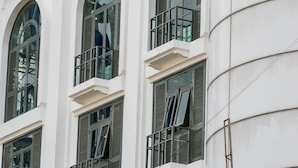A building with multiple windows, some with shutters, and a white facade.