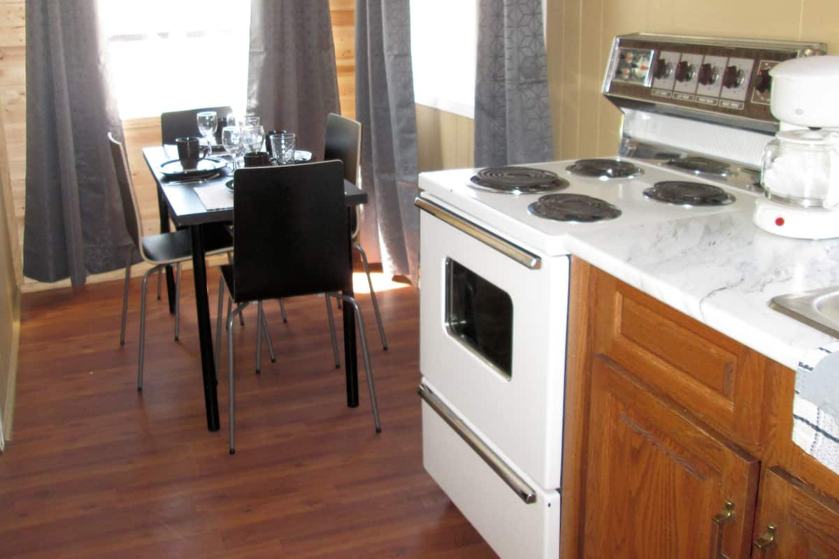 A compact kitchen with a stove, oven, and a dining table with chairs.