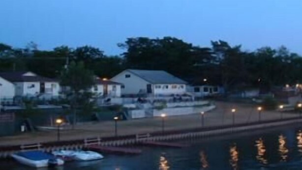 A waterfront property with a dock, boats, and houses along the shore. - Edgewater Resorts - Edgewater Cottages (Wasaga Beach)