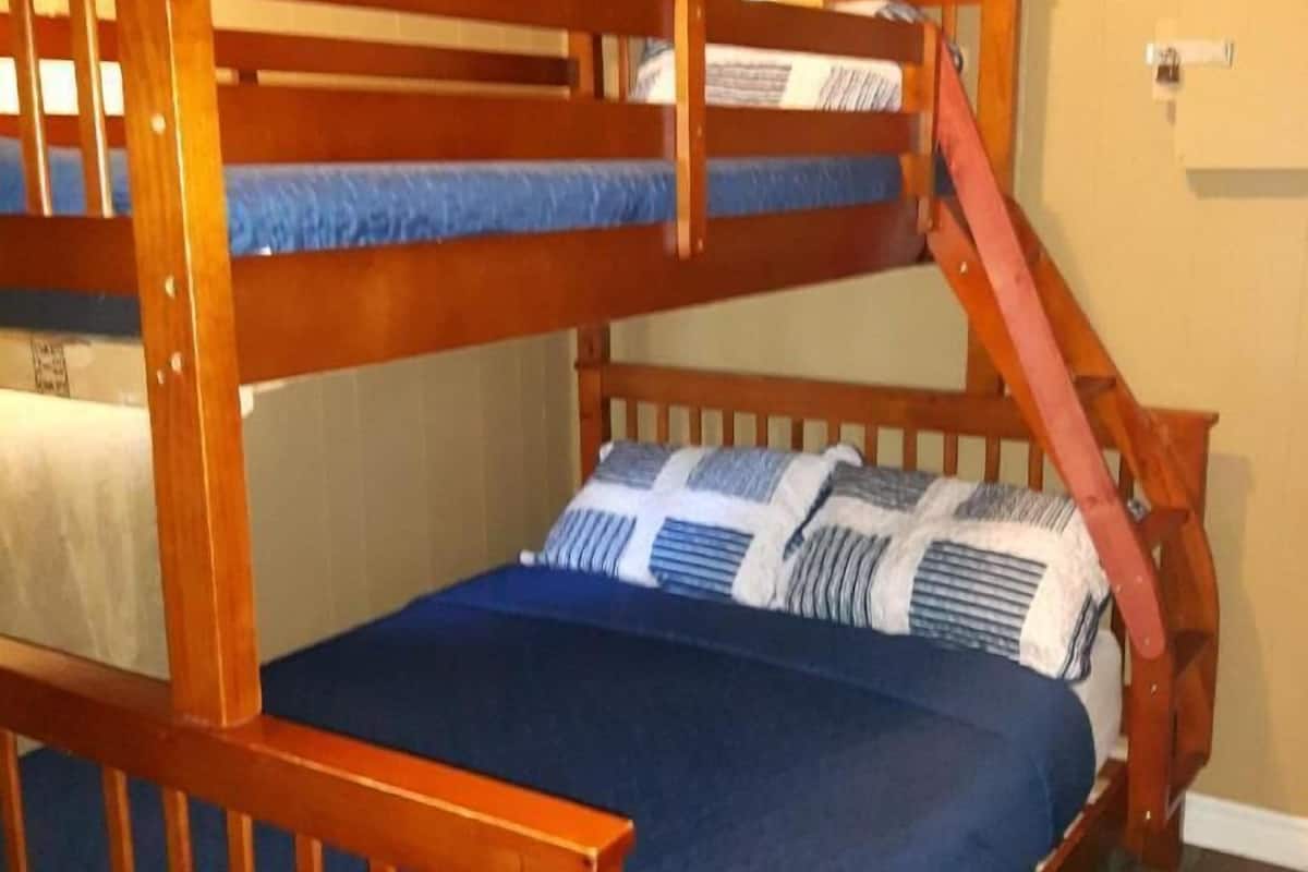 A bunk bed with a wooden frame and blue bedding.