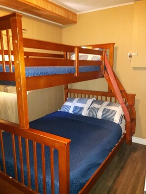 A bunk bed with a wooden frame and blue bedding. - Edgewater Resorts - Edgewater Cottages (Wasaga Beach)
