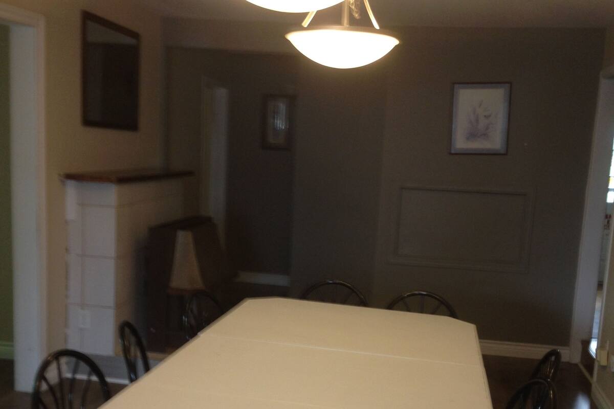 A dining area with a rectangular table and chairs, a chandelier, and a fireplace.