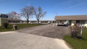 Un motel con estacionamiento, varios coches y una bandera canadiense.