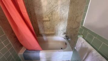 A bathroom with a bathtub, a shower curtain, and a towel rack.