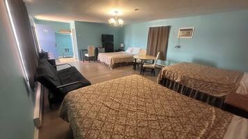 A hotel room with two beds, a desk, a chair, a television, and a window with curtains.