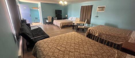 A hotel room with two beds, a desk, a chair, a television, and a window with curtains.