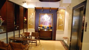 A hotel lobby with wooden furniture, a reception desk, and decorative panels. - Rambuttri House (Bangkok)