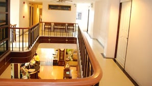A hotel lobby with a high ceiling, a central staircase, and a seating area. - Rambuttri House (Bangkok)