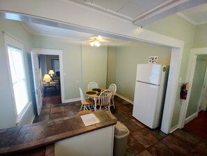 A kitchen with a dining table, chairs, a refrigerator, and a trash can. - Mount Dora Cottages (Mount Dora)