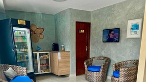 A reception area with wicker chairs, a refrigerator, a cabinet, and a fire extinguisher. - Hotel Pousada Alagoana (Maceió)