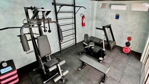 A gym with exercise equipment, a bench, and a weight bench. - Hotel Pousada Alagoana (Maceió)