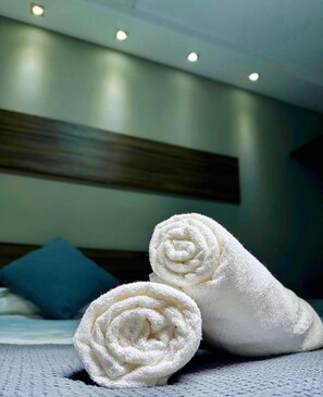 A neatly made bed with two rolled white towels in front. - Hotel Pousada Alagoana (Maceió)