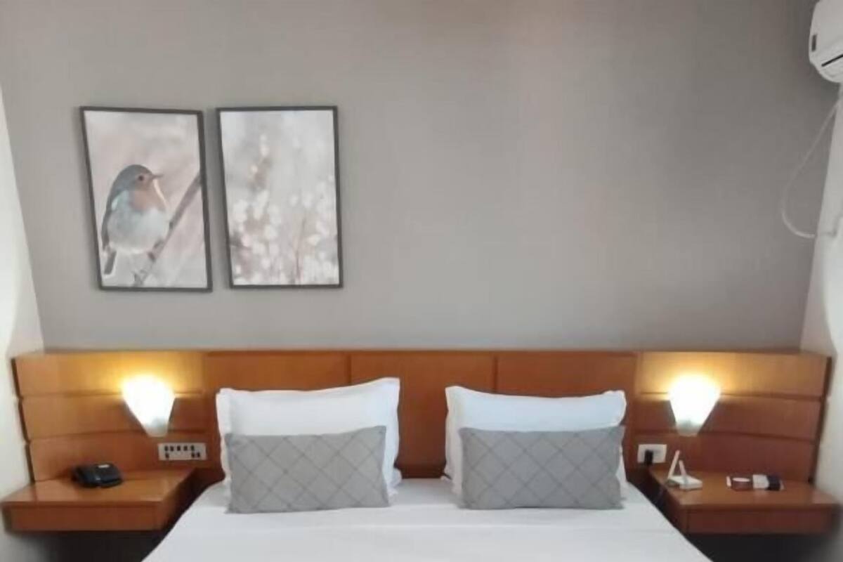A double bed with a quilted bedspread, two bedside tables with lamps, and two framed pictures on the wall.