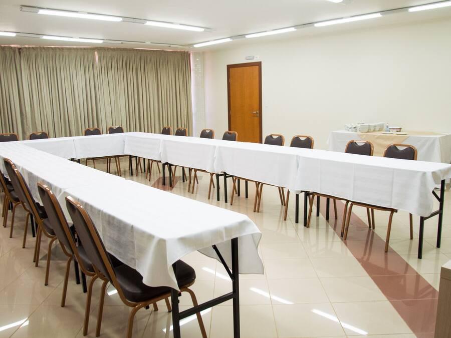 Un salón de conferencias con una larga mesa, sillas y una pequeña mesa cubierta con un mantel.