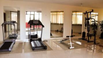 Ein geräumiges Fitnessstudio mit Laufband, Crosstrainer und Kraftmaschine.