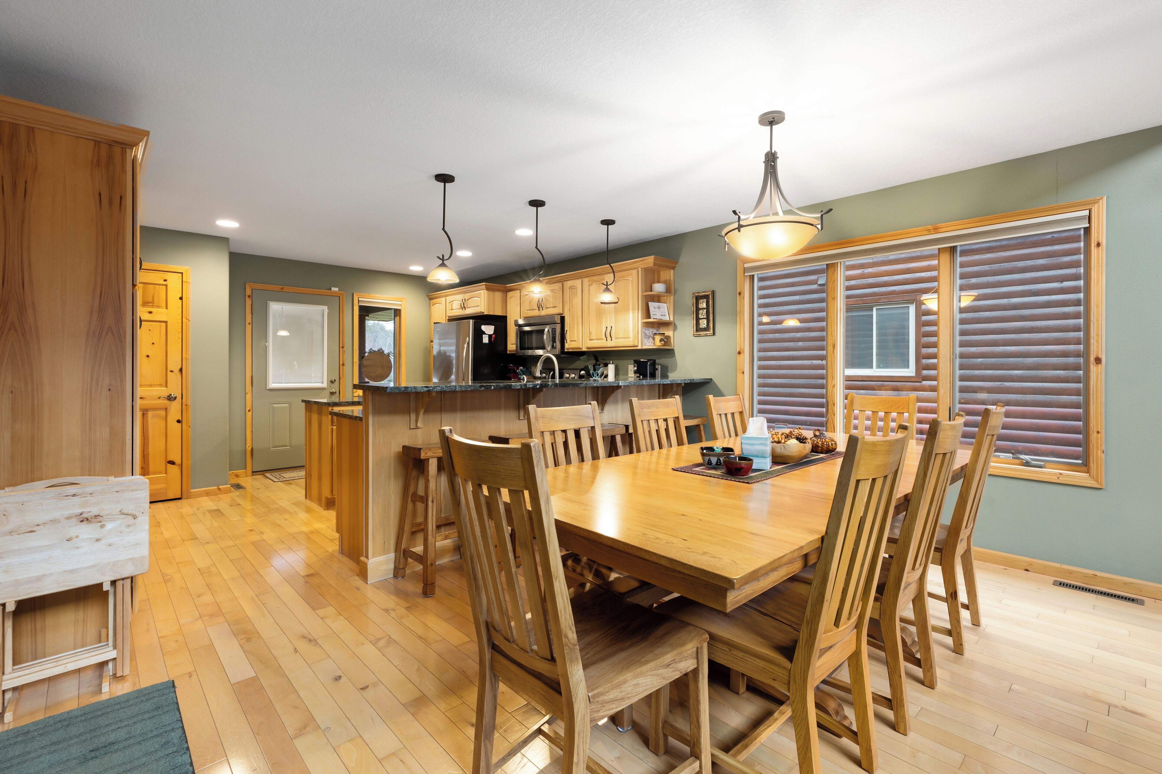 Una cocina amplia con armarios de madera, una isla central y un comedor con mesa y sillas de madera.