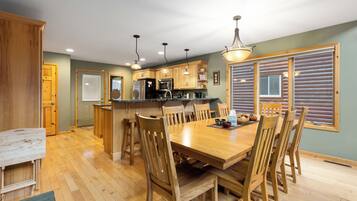 Una cocina amplia con armarios de madera, una isla central y un comedor con mesa y sillas de madera.